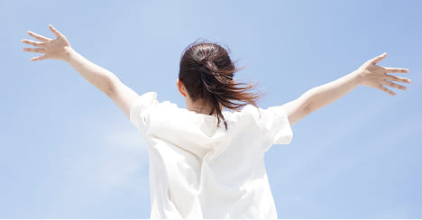 両手を広げて自然の中で気持ちよさそうにする女性